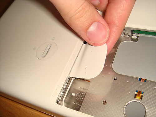 The white plastic tab that can be pulled to remove the hard disk drive tray in a 2006 Polycarbonate MacBook.