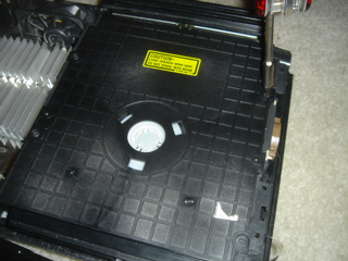 Removing the screws atop a PlayStation 2 console's DVD drive.