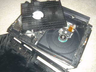 A PlayStation 2 console's open top-case with the top-case of the DVD drive also removed.