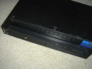 Applying electrical tape to the front underside case intersection to allow hinged opening on a PlayStation 2 console.